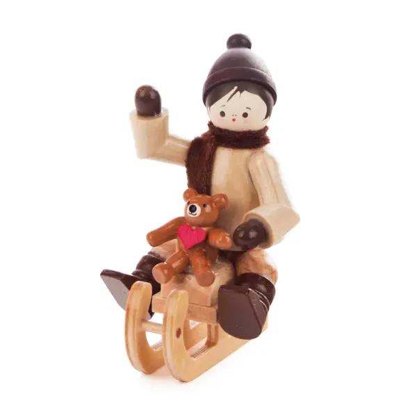 Winterkind mit Teddy auf Schlitten